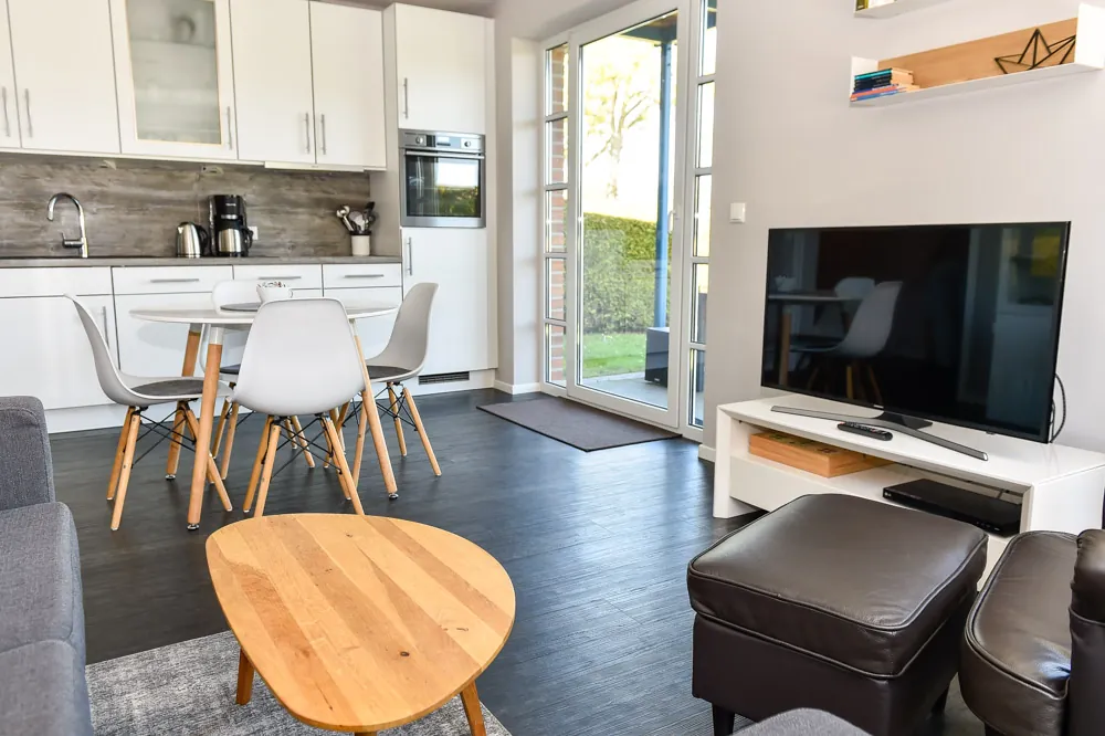 Blick vom Wohnbereich mit Fernseher und Sofa in Richtung Küche